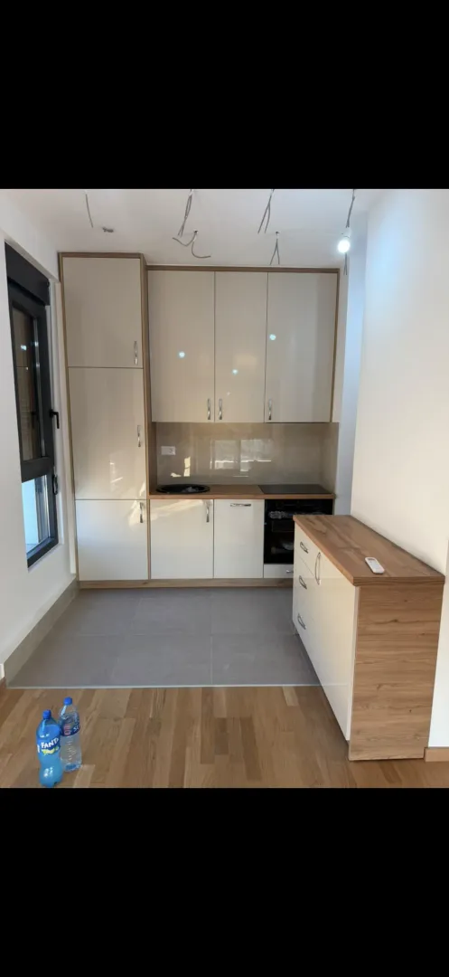 Small modern kitchen with beige cabinets and wood details.