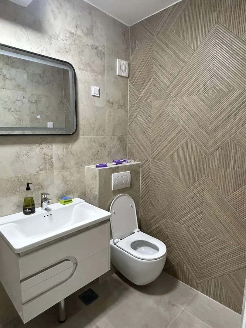 Modern bathroom featuring a sink, mirror, and decorative tiled wall.