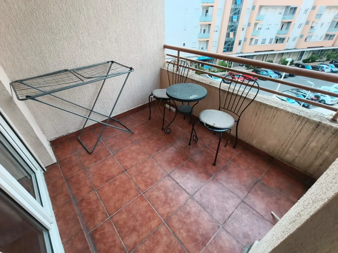 Manji namješten balkon sa stolom, stolicama i sušilicom za veš.