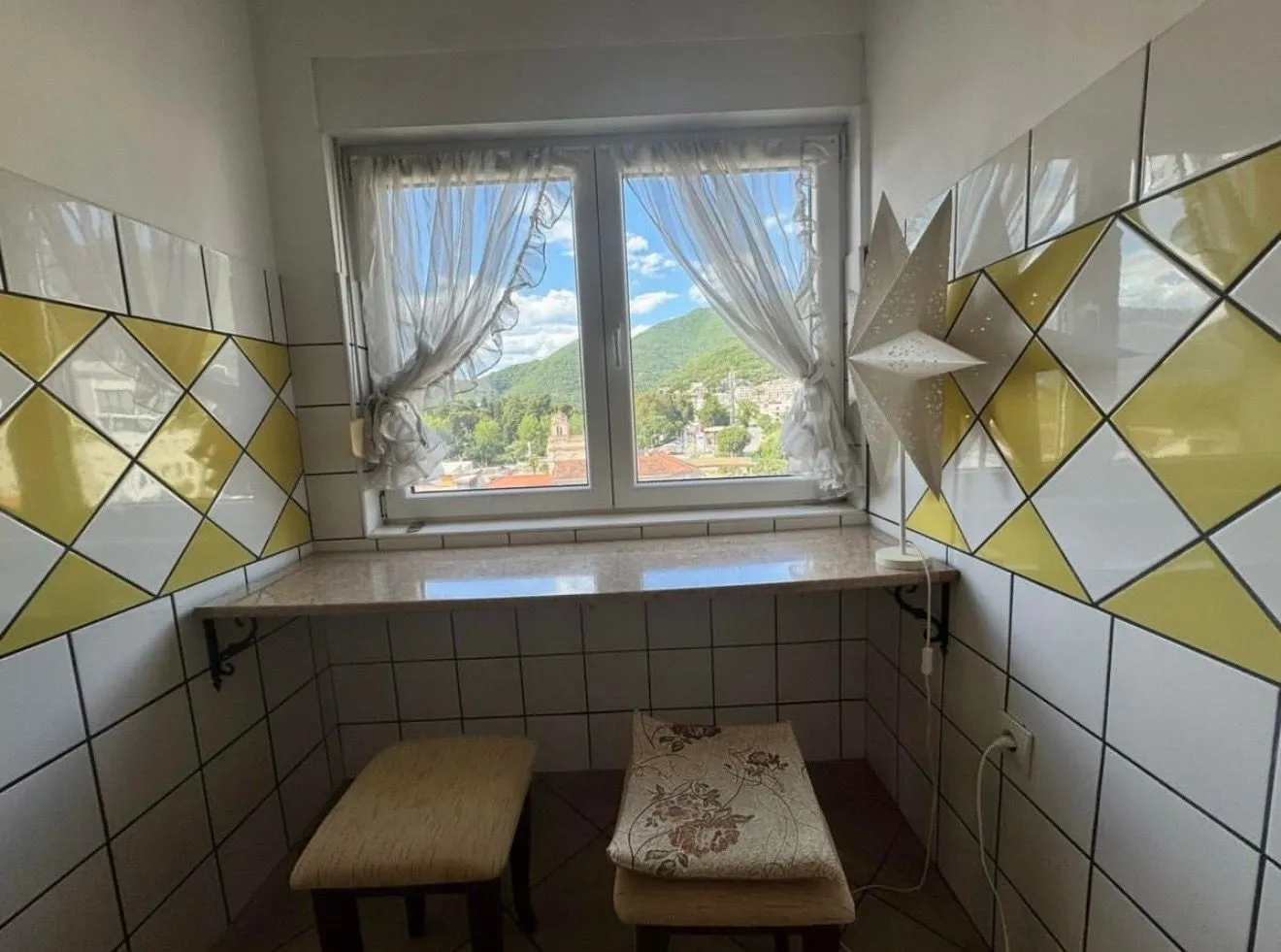 Mala kuhinja sa pultom i pogledom na prirodu.