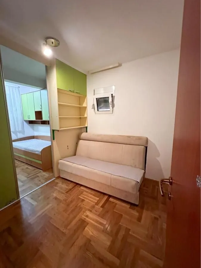 Manja spavaća soba sa kaučem i pogledom na susjednu prostoriju sa krevetom.