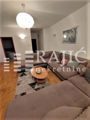 Spacious living room with a sectional sofa and parquet flooring.