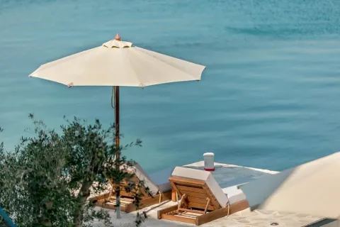 Ležaljke pod suncobranom na kamenoj terasi pored mora. - image 18