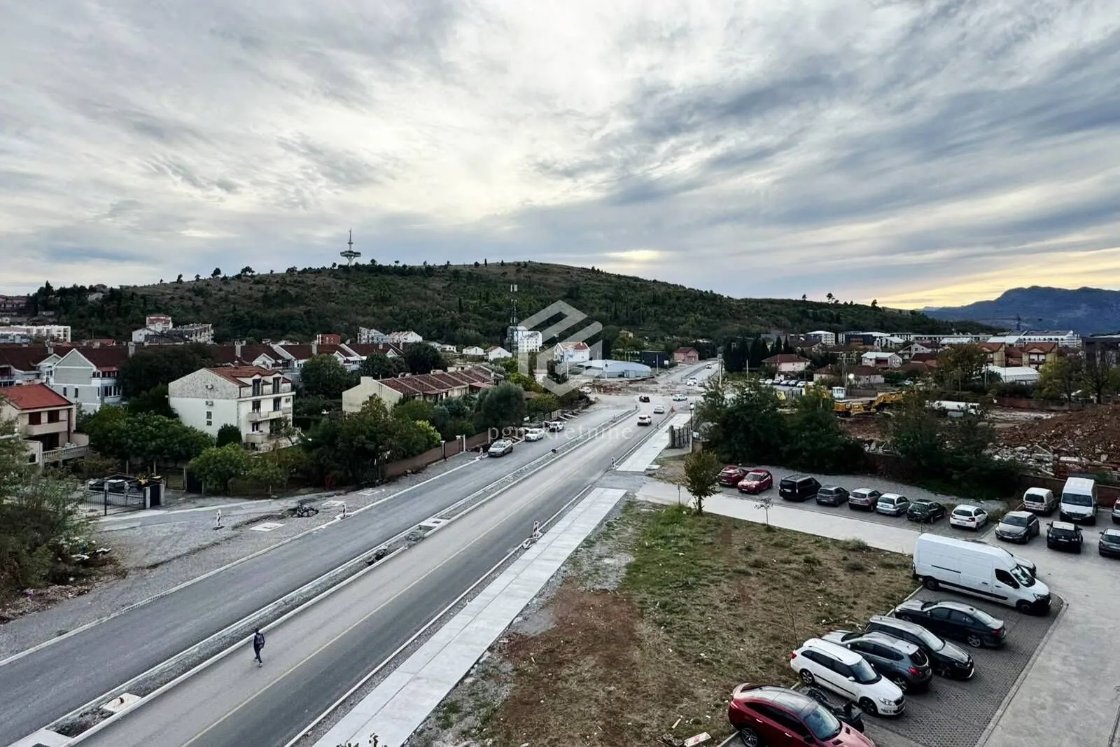 Pogled sa prozora na okolno naselje i brdo.