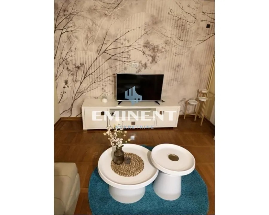 Living room with furniture, TV unit and decorative wallpaper on the wall.
