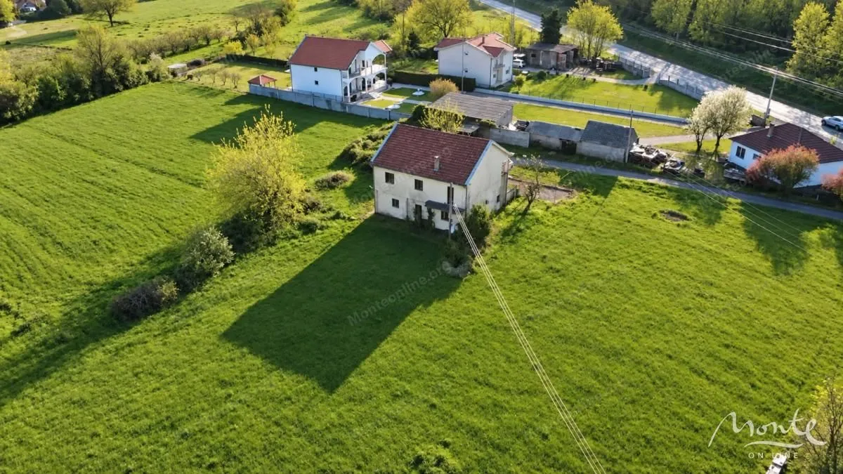 Pogled iz vazduha na kuću sa velikim dvorištem i zelenilom.