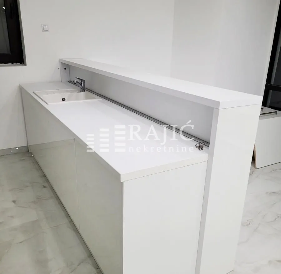 Modern white kitchen with sink and bar counter.