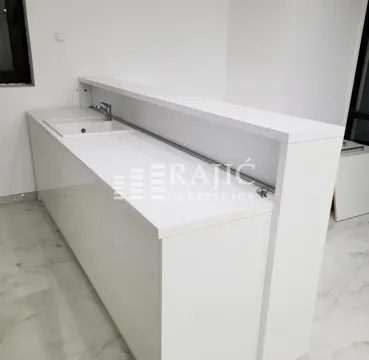 Modern white kitchen with sink and bar counter. - image 7
