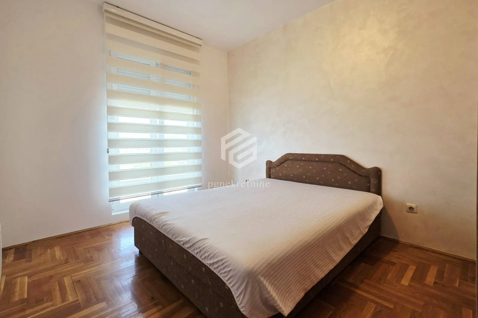 Bedroom with a double bed and a window with blinds.