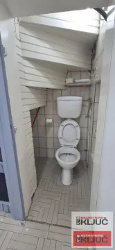 Small bathroom with a toilet located under the stairs. - image 9