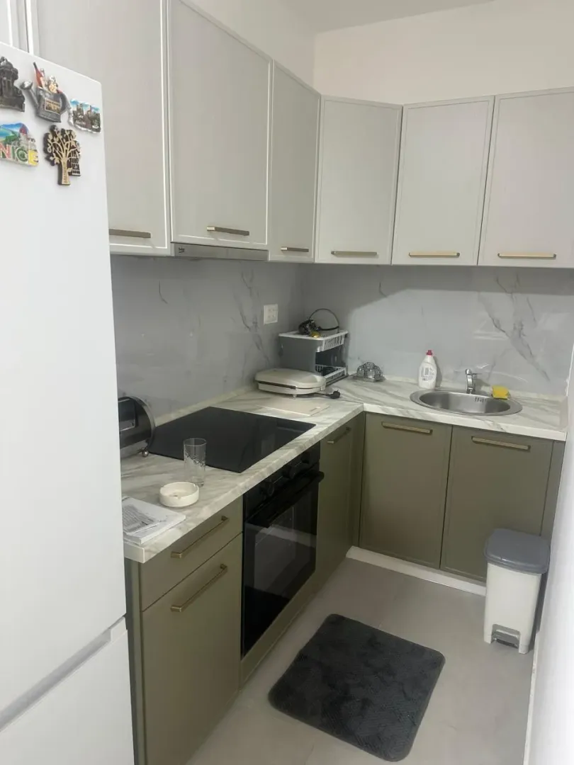 Small kitchen with light upper and olive green lower cabinets.
