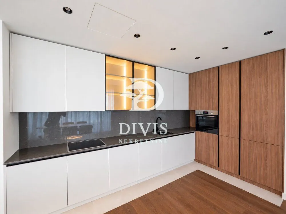 Modern kitchen with white cabinets, wooden fronts, and a built-in oven.