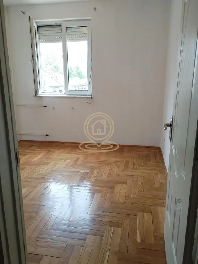 Prazna soba sa parketom i prozorom.