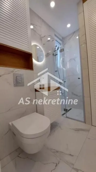 Savremeno opremljeno kupatilo sa tuš kabinom i mermernim pločicama.
