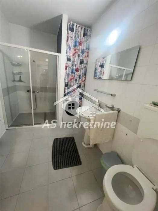 Bathroom with a shower cabin, washbasin, toilet, and washing machine.