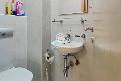 Manje kupatilo sa umivaonikom, ogledalom i toaletom obloženo svijetlim keramičkim pločicama. - image 4