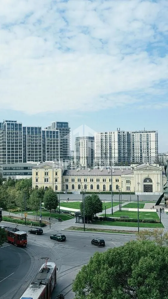 Pogled sa prozora na gradski trg, saobraćajnicu i moderne zgrade u pozadini.