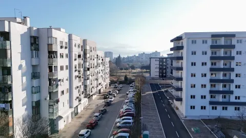 Exterior view of residential buildings and a parking lot under a clear sky. - image 16