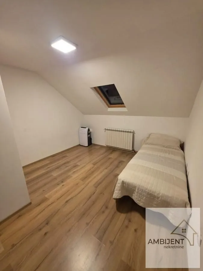 Attic bedroom with a bed, laminate flooring, and a skylight.