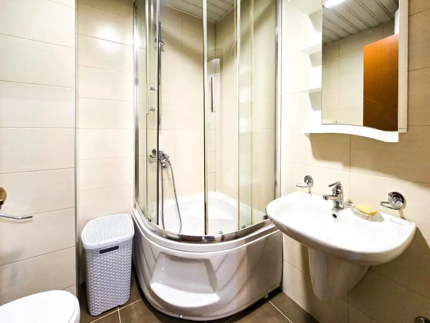A bright bathroom featuring a shower cabin, a sink, and a mirror.