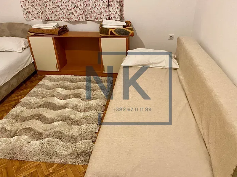 Namještena spavaća soba sa dva kreveta i tepihom.