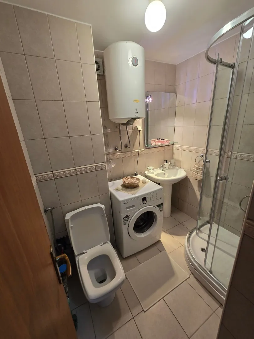 Smaller bathroom equipped with sanitary ware, a shower cabin, and a washing machine.