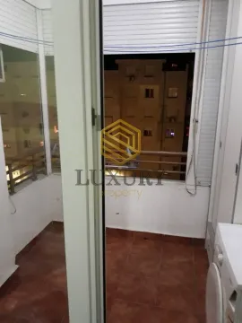Enclosed balcony overlooking neighboring buildings. - image 2