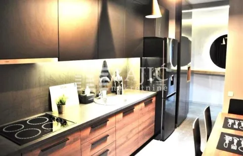 Modern kitchen with dark cabinetry and a dining table. - image 7