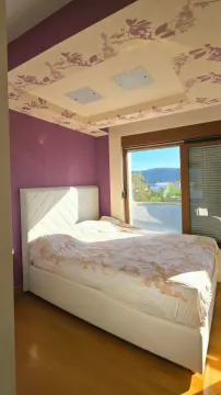 Spavaća soba sa bračnim krevetom, ljubičastim zidom i dekorativnim plafonom. - image 8