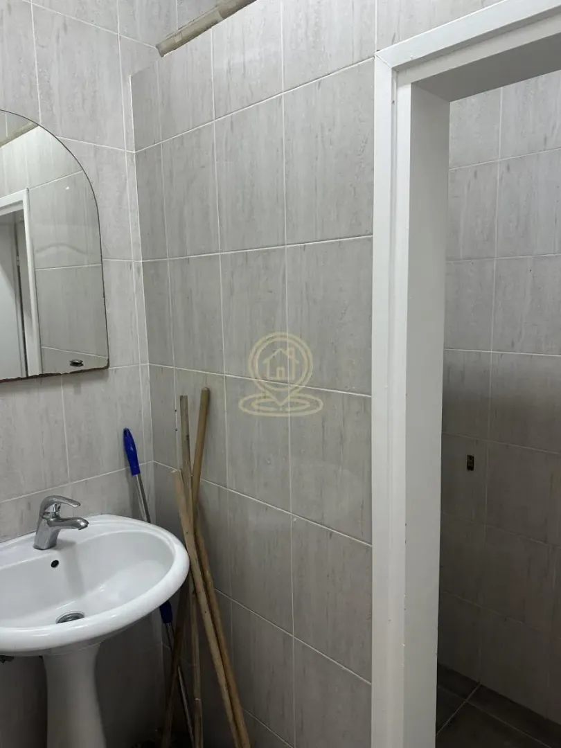 Small bathroom tiled in grey with a washbasin and mirror.