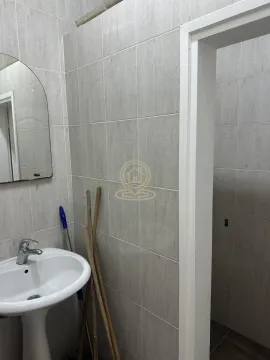 Small bathroom tiled in grey with a washbasin and mirror. - image 8