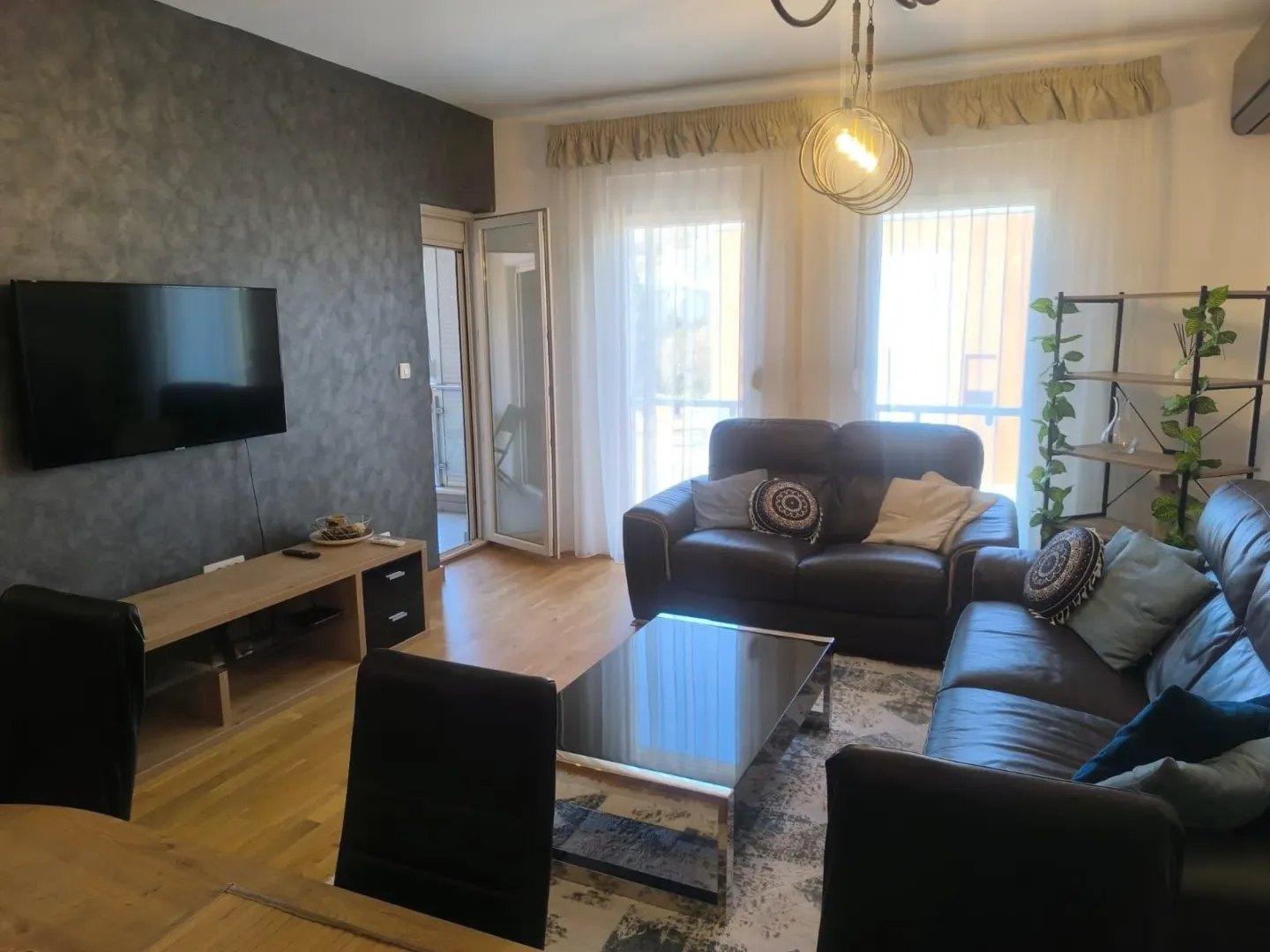 Spacious and bright living room with a sofa set, TV, and access to the terrace.