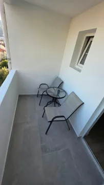 Small covered balcony with patio furniture and a view of the surroundings. - image 12