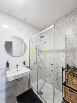 Modern bathroom with a walk-in shower, washbasin, and round mirror. - image 16