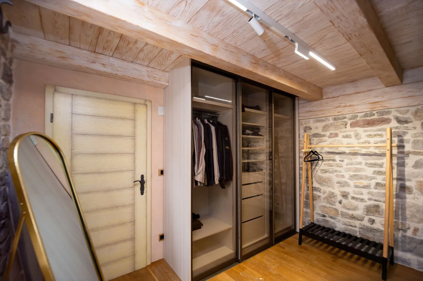 Bedroom with a fitted wardrobe, wooden ceiling, and a stone wall.