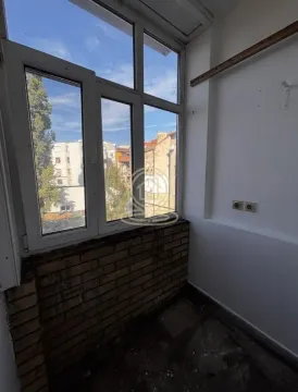 Enclosed balcony with a view of neighboring buildings. - image 6