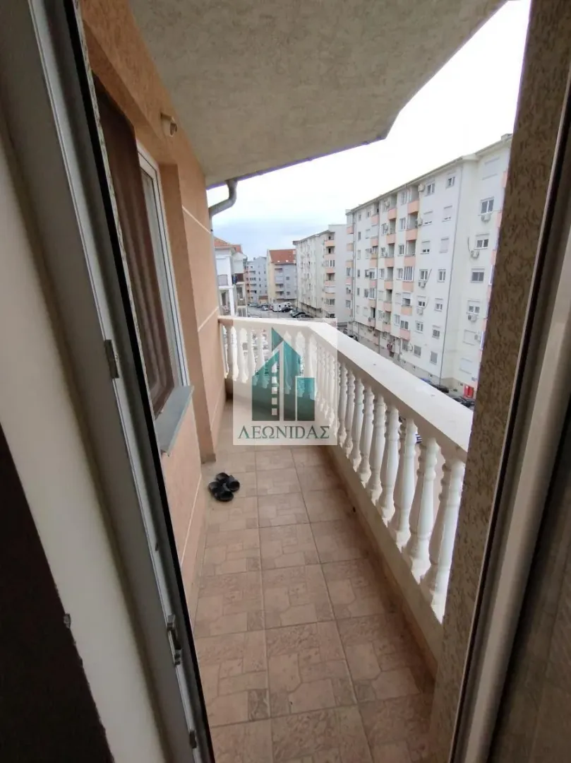 Long balcony with ceramic tiles and a view of the neighborhood and buildings.