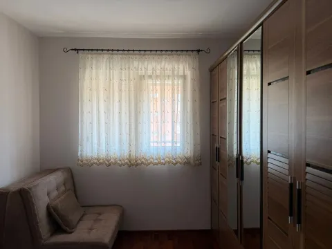 Small bedroom with a sofa bed, sheer curtains, and a large wooden wardrobe with a mirror. - image 2