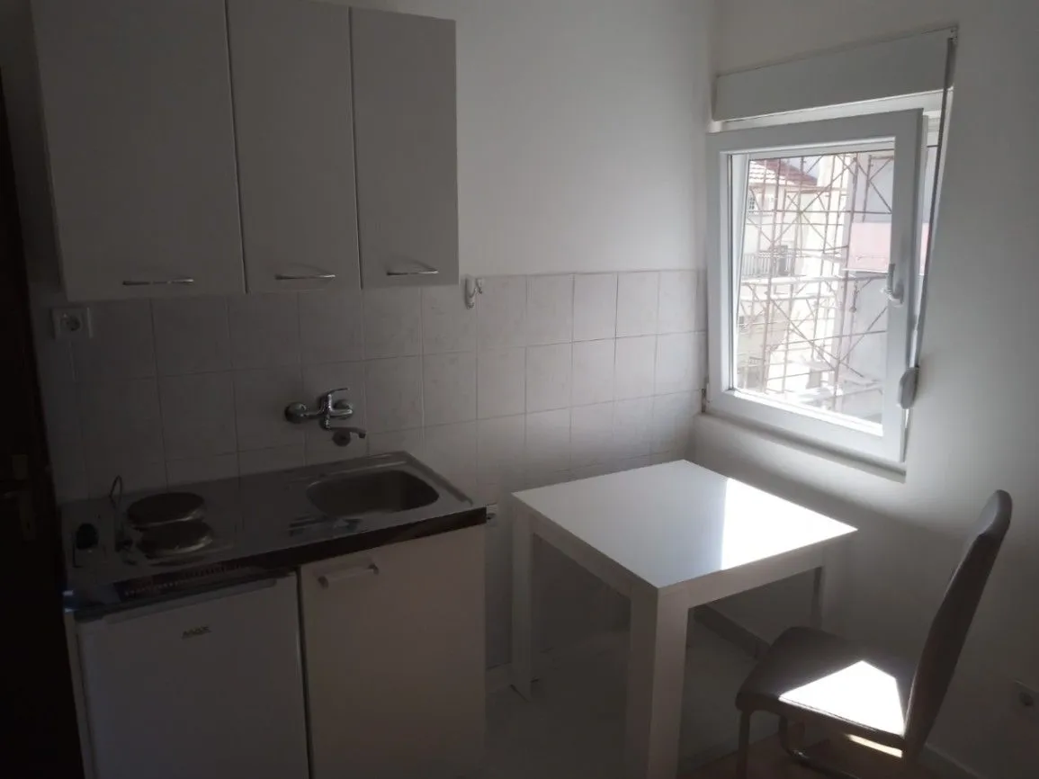 Small kitchen with a sink, built-in units, and a dining table by the window.