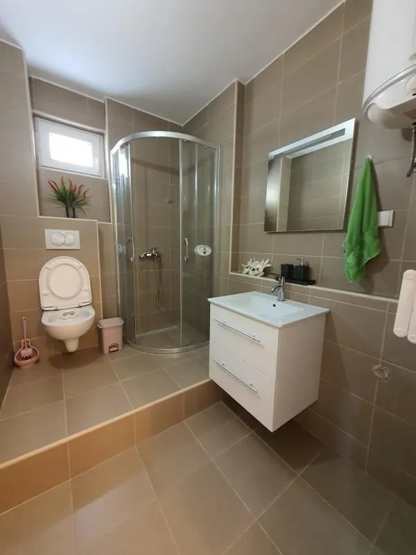 Kupatilo opremljeno tuš kabinom, umivaonikom i WC šoljom.