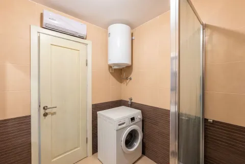 Bathroom with a washing machine, water heater, and shower cabin. - image 9