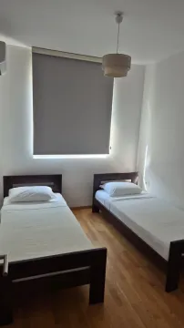 Bedroom with two single beds and parquet flooring. - image 21
