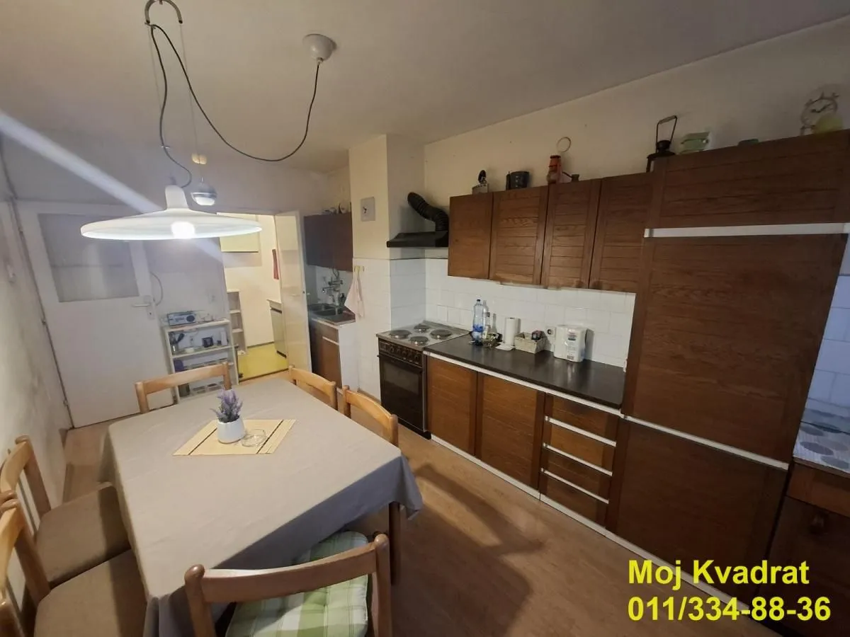 Kuhinja sa trpezarijom i drvenim elementima.