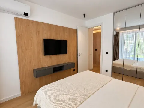 Moderna i uredna spavaća soba sa bračnim krevetom, TV panelom i plakarom sa ogledalom. - image 7