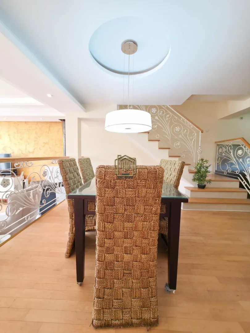 Dining area with a wooden table and wicker chairs situated in an open-plan space.