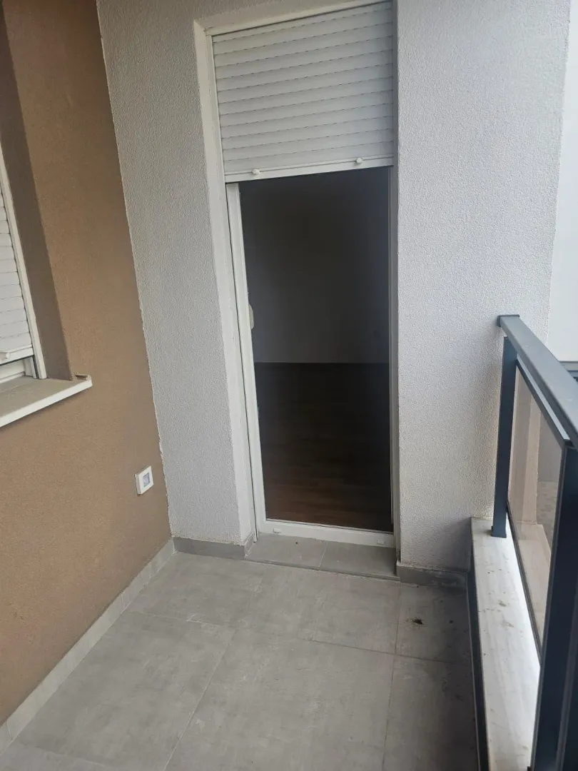 Manji popločani balkon sa pogledom na ulazna vrata u unutrašnjost stanovanja.