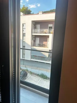 Pogled kroz prozor na susjednu zgradu i parking. - image 6