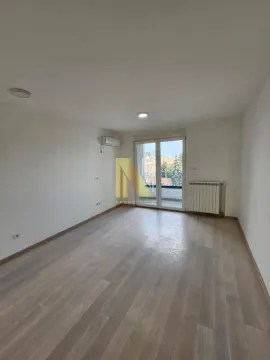 Prazna svetla prostorija sa drvenim podom i izlazom na terasu. - image 6