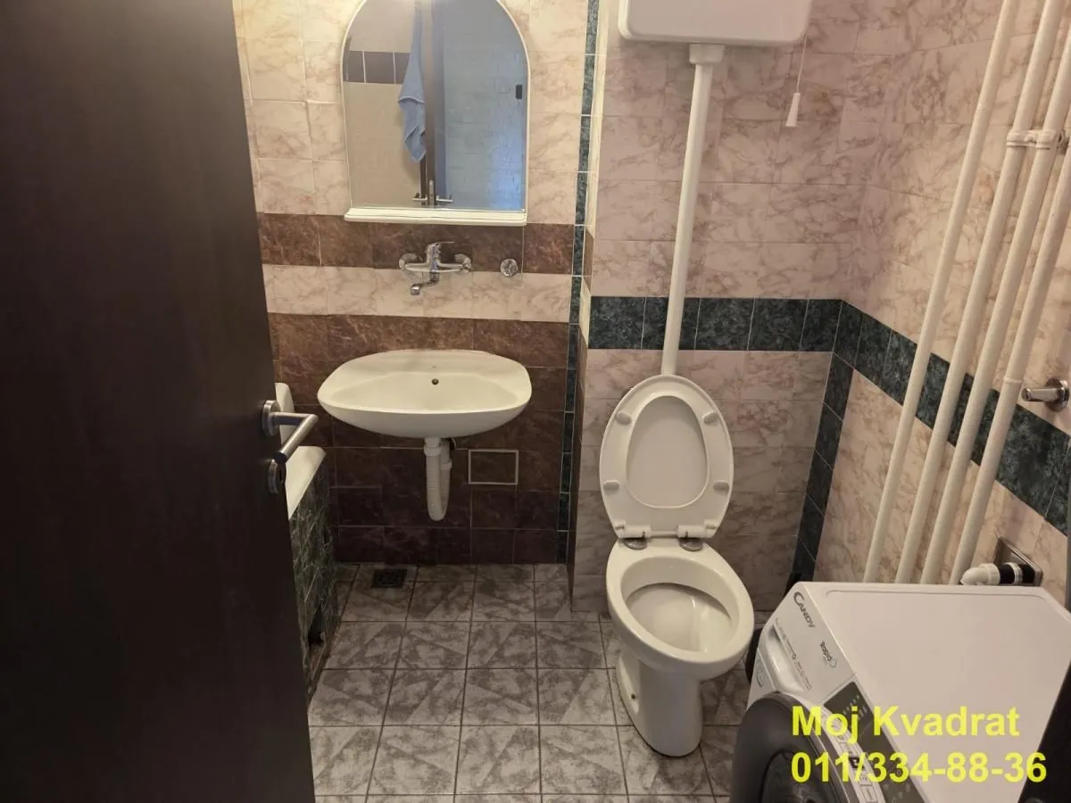 Manje kupatilo sa umivaonikom, WC šoljom i mašinom za veš.