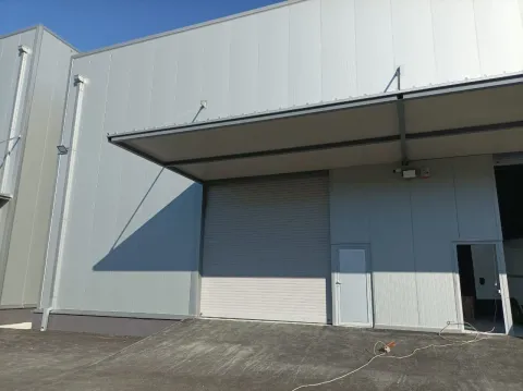 Exterior of a modern warehouse with a roller shutter door and a ramp. - image 2